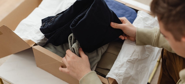 How to pack clothes for moving like a pro 4 Person unpacking a wardrobe box after using the best way to pack clothes for moving.