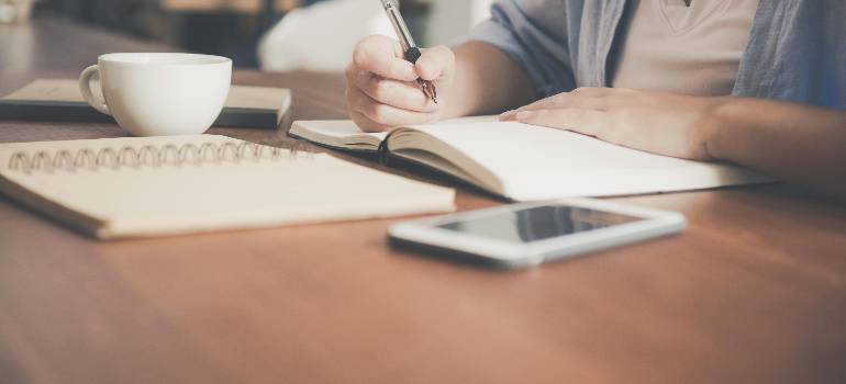 Top places in the Greater Cincinnati metro area for young professionals 4 Person planning relocation with notebook, coffee, and phone