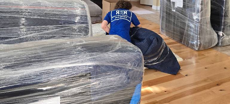 How to dispose of leftover packing materials after moving to Cincinnati? 1 Mover wrapping sofa, with packing materials after moving to Cincinnati